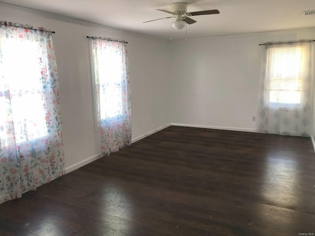 empty room featuring a ceiling fan, baseboards, a healthy amount of sunlight, and hardwood / wood-style floors