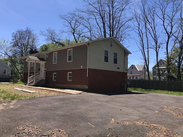 view of home's exterior with brick siding, fence, driveway, and a chimney