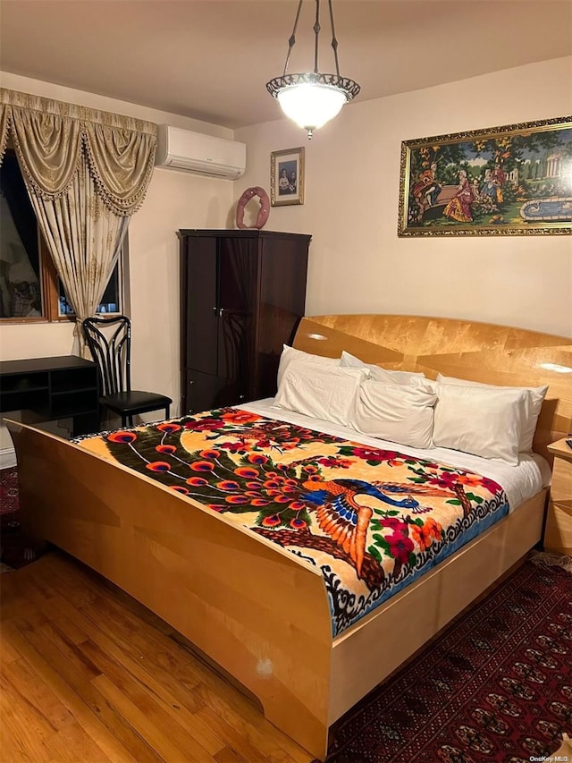 bedroom featuring hardwood / wood-style flooring and a wall unit AC