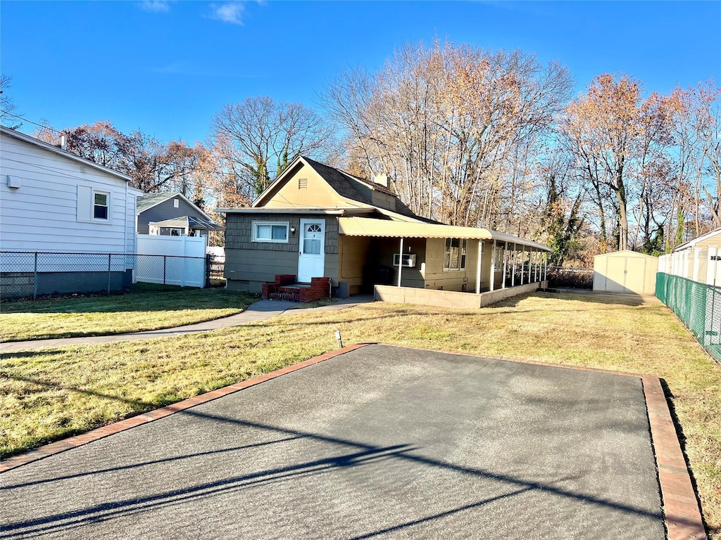 view of front facade featuring a front yard and a storage shed