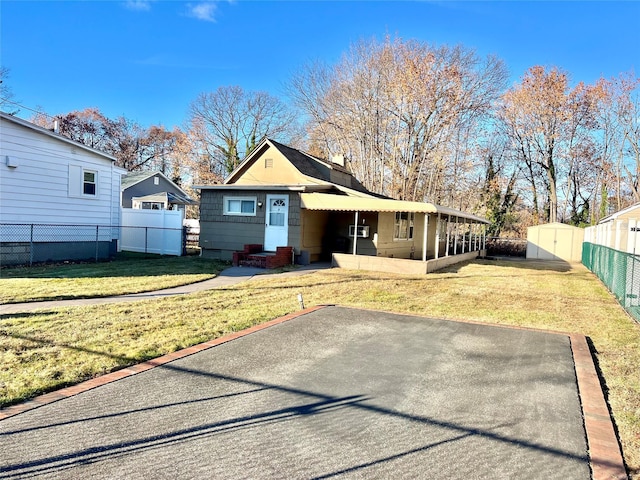 view of front facade featuring a front yard and a storage shed