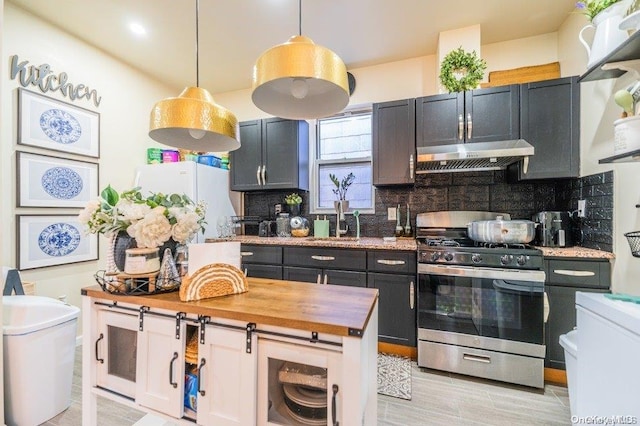 kitchen featuring white refrigerator, light hardwood / wood-style flooring, stainless steel range, tasteful backsplash, and decorative light fixtures