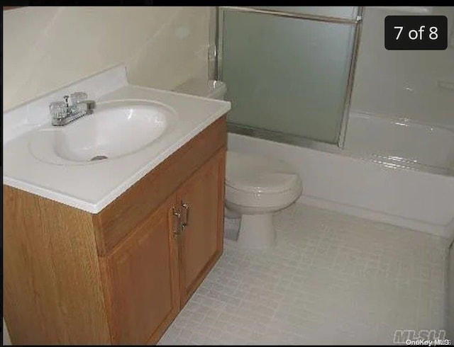 full bathroom featuring shower / bath combination with glass door, vanity, toilet, and tile patterned flooring