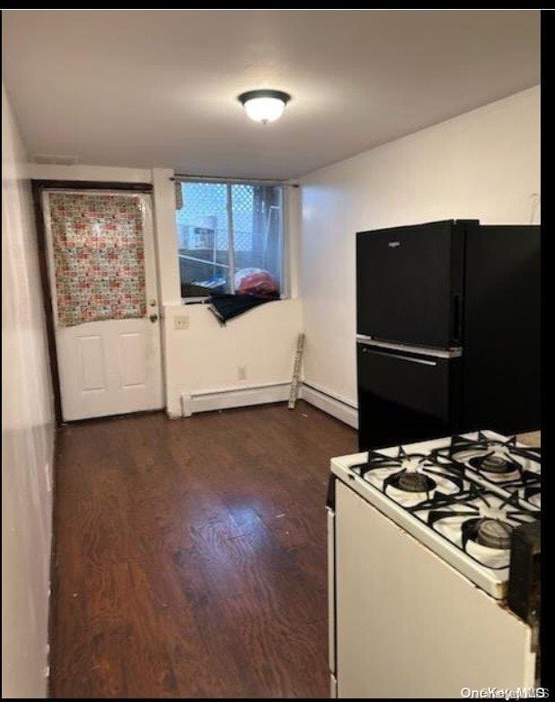 kitchen featuring white gas range, black refrigerator, a baseboard radiator, and dark hardwood / wood-style flooring