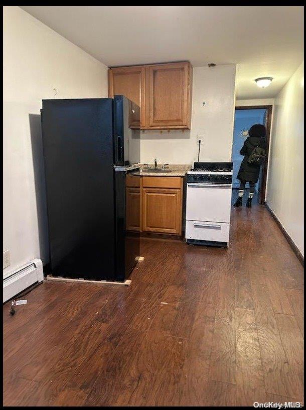 kitchen featuring dark hardwood / wood-style flooring, white range oven, black fridge, and sink