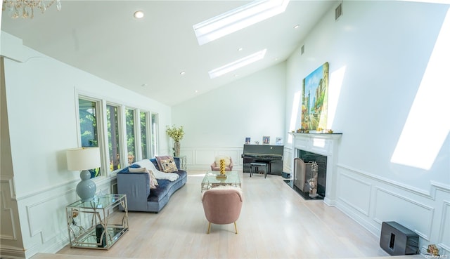 living room featuring a skylight, high vaulted ceiling, and light hardwood / wood-style flooring