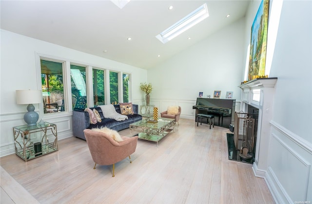 living room featuring high vaulted ceiling, a skylight, and light hardwood / wood-style flooring