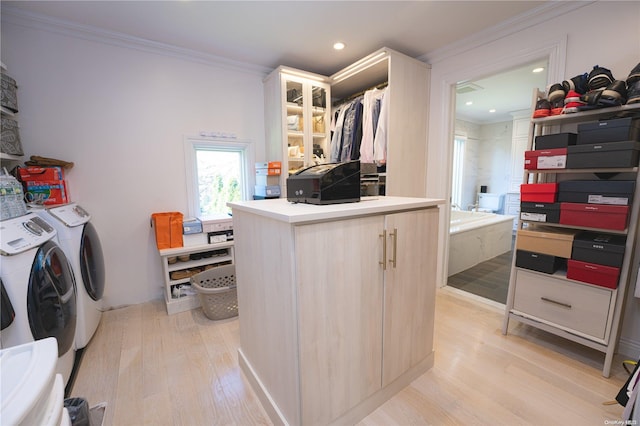 washroom featuring crown molding, light hardwood / wood-style flooring, and washing machine and clothes dryer