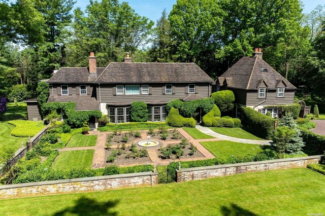 285 Piping Rock Rd, Locust Valley, NY 11560 - view of front of house with a front lawn, a chimney, and view of wooded area