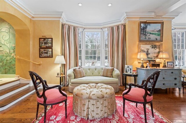 living area with wood-type flooring and ornamental molding