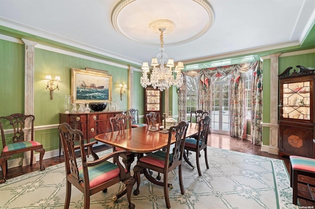 dining area with decorative columns, crown molding, light hardwood / wood-style flooring, and a notable chandelier