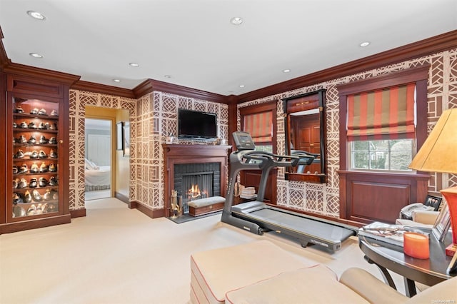 exercise room featuring a brick fireplace, light carpet, and ornamental molding