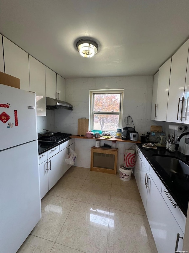 kitchen with white cabinetry, sink, and white refrigerator