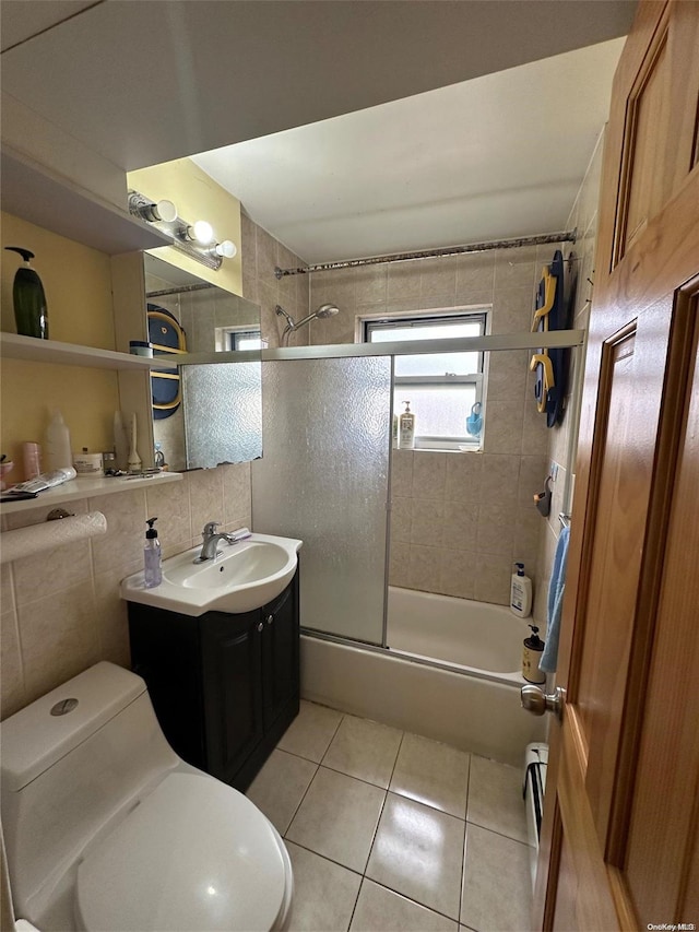 full bathroom with vanity, shower / bath combination with glass door, tile patterned flooring, toilet, and tile walls