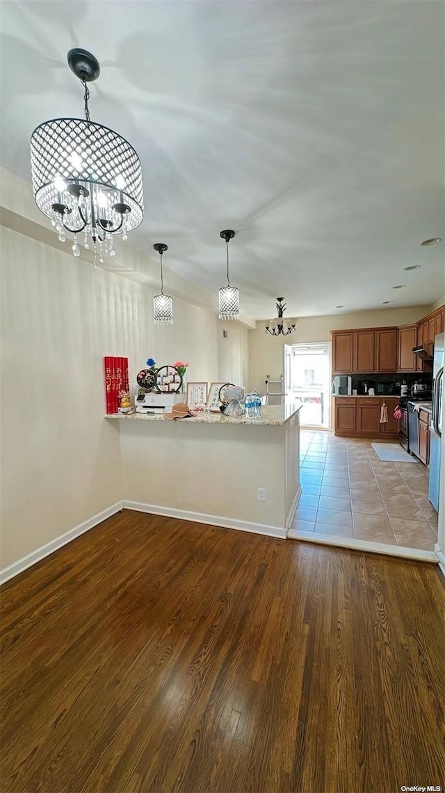 kitchen featuring light hardwood / wood-style flooring, kitchen peninsula, a chandelier, pendant lighting, and appliances with stainless steel finishes