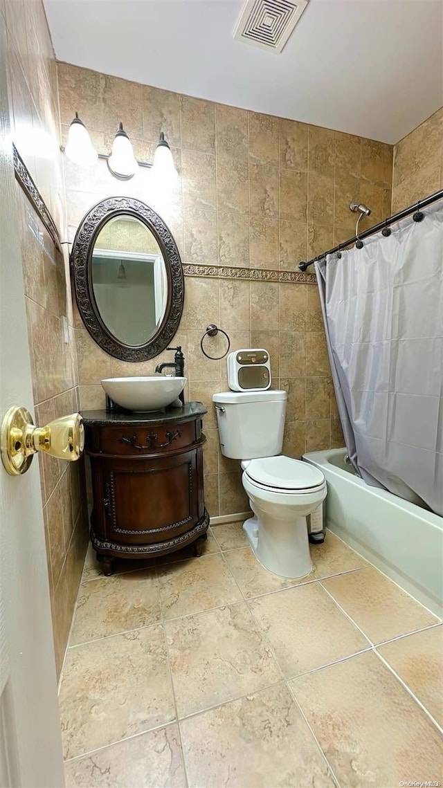 full bathroom with vanity, toilet, tile walls, and shower / tub combo with curtain