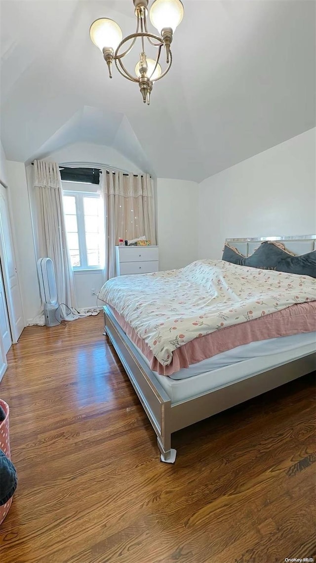 bedroom with vaulted ceiling, dark hardwood / wood-style floors, and an inviting chandelier