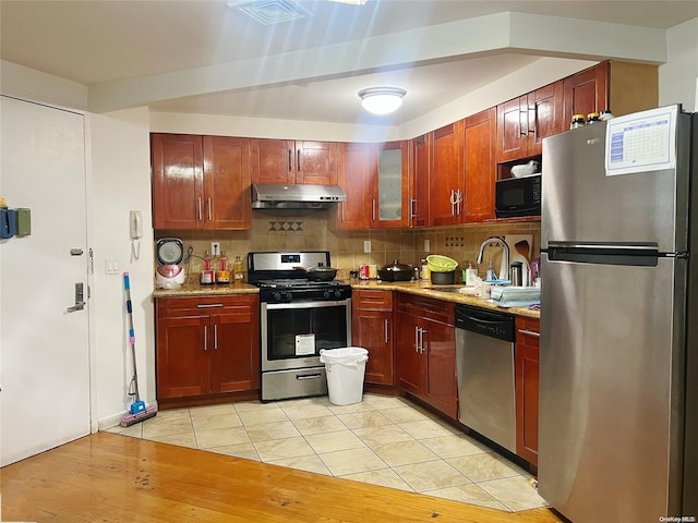 kitchen with sink, light stone counters, backsplash, light hardwood / wood-style floors, and appliances with stainless steel finishes