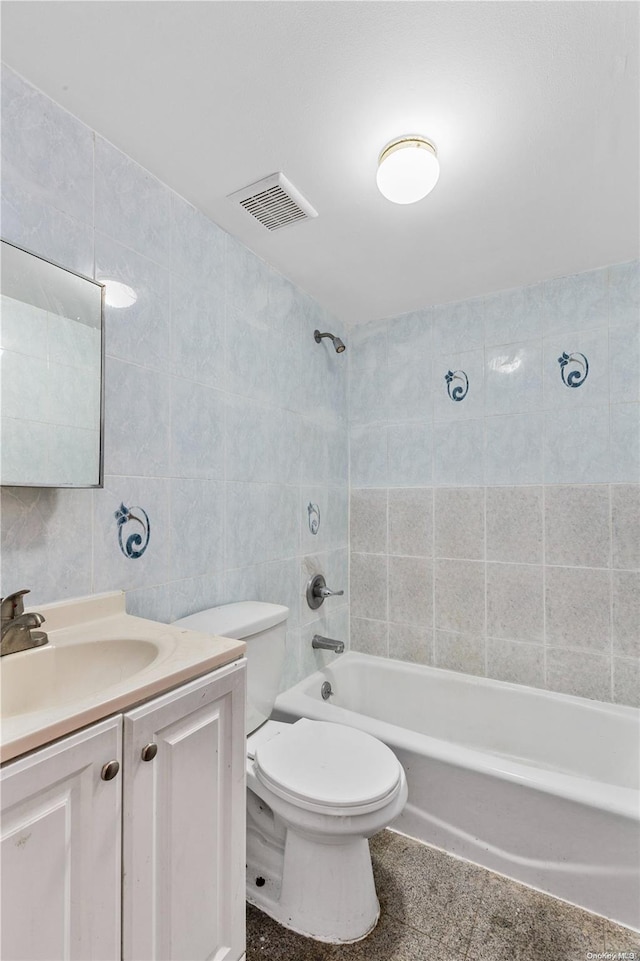 full bathroom with vanity, toilet, tile walls, and tiled shower / bath