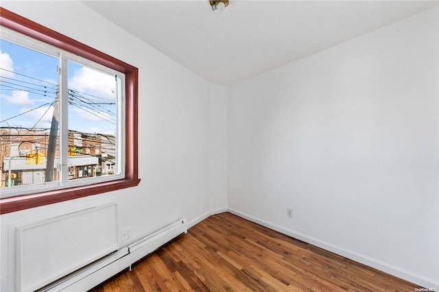 empty room with hardwood / wood-style floors and a baseboard radiator