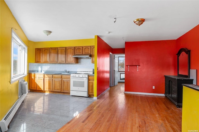 kitchen featuring sink, white gas stove, baseboard heating, tasteful backsplash, and light wood-type flooring