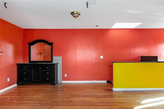 unfurnished bedroom with a skylight and hardwood / wood-style flooring