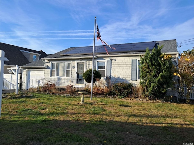 view of front of home featuring a garage, a front yard, and solar panels