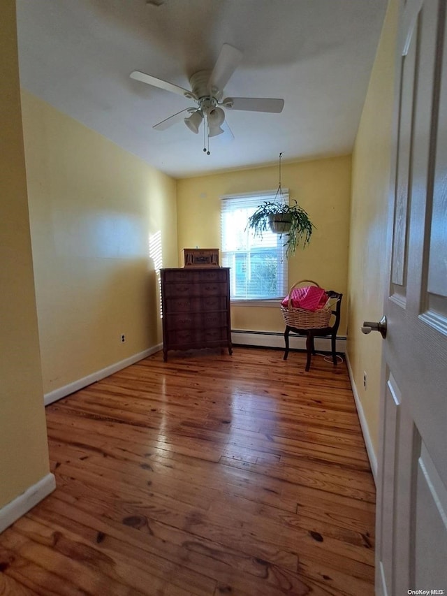 unfurnished room with ceiling fan, hardwood / wood-style floors, and a baseboard heating unit