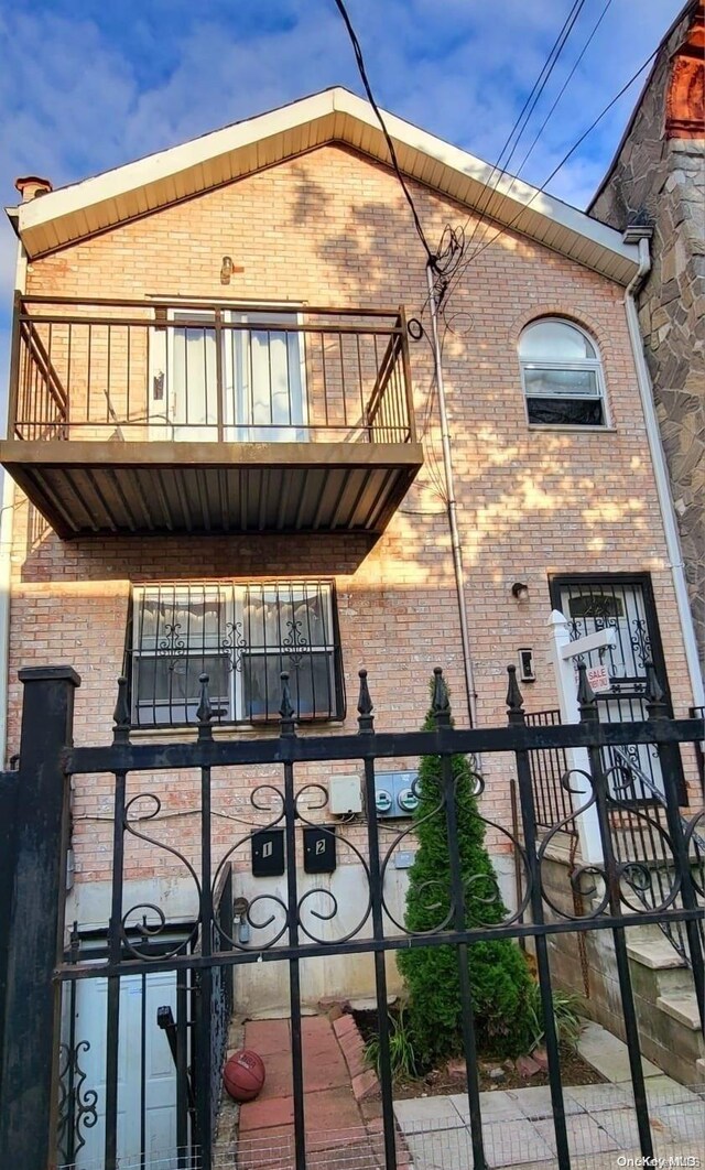 607 Ashford St, Brooklyn, NY 11207 - view of side of home featuring a balcony, brick siding, and a fenced front yard