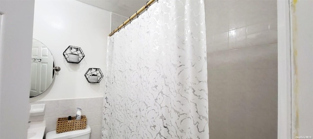 bathroom featuring toilet, curtained shower, and tile walls