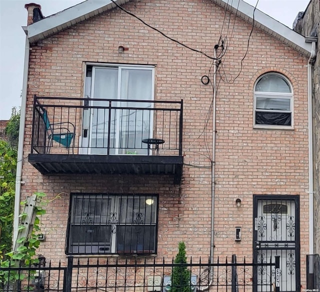 607 Ashford St, Brooklyn, NY 11207 - view of side of home with a balcony, a fenced front yard, and brick siding