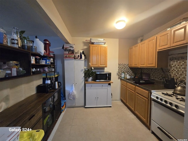 607 Ashford St, Brooklyn, NY 11207 - kitchen with white gas range oven, stainless steel microwave, tasteful backsplash, dark countertops, and light tile patterned floors