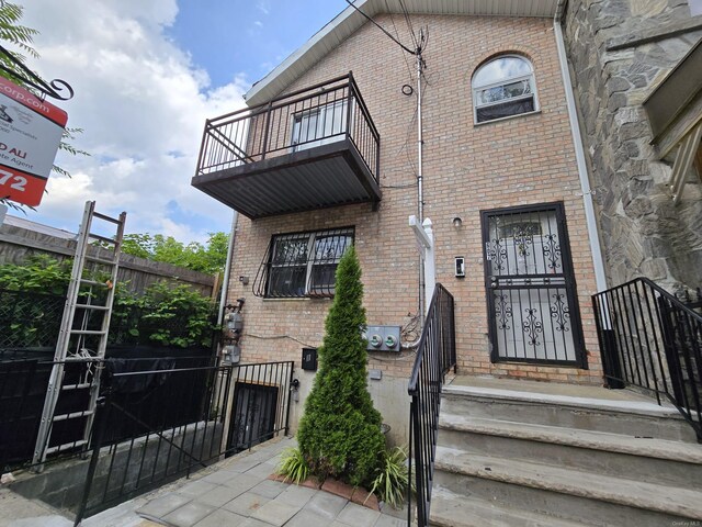 607 Ashford St, Brooklyn, NY 11207 - property entrance with a balcony, brick siding, and a gate
