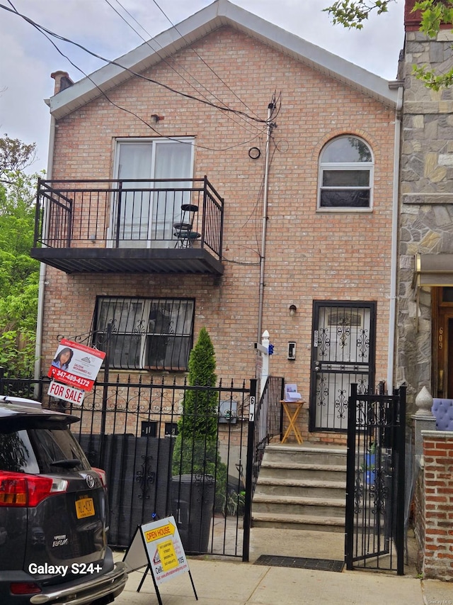 607 Ashford St, Brooklyn, NY 11207 - view of front facade with brick siding, a gate, a balcony, and a fenced front yard