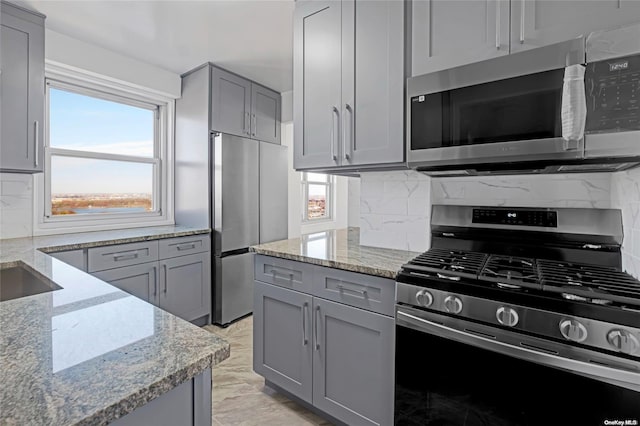 kitchen with light stone counters, appliances with stainless steel finishes, and tasteful backsplash