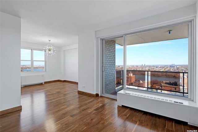 spare room with radiator heating unit, dark hardwood / wood-style floors, and a notable chandelier