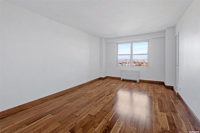 spare room featuring dark hardwood / wood-style flooring and radiator heating unit