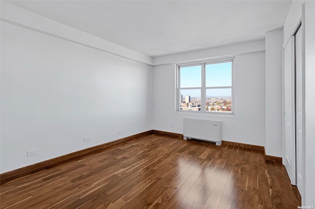 empty room featuring dark wood-type flooring and radiator