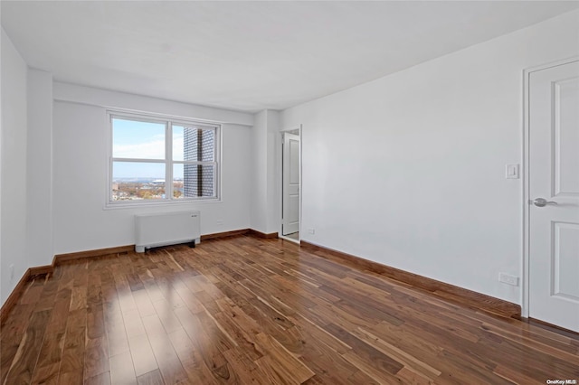 spare room with radiator and dark wood-type flooring