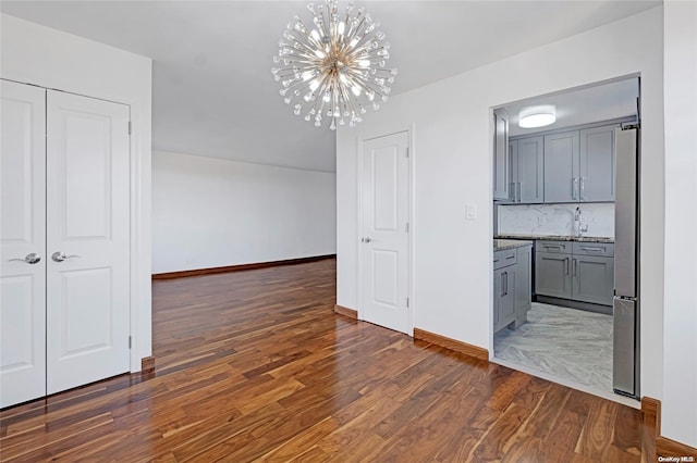 unfurnished dining area featuring sink, dark hardwood / wood-style floors, and a notable chandelier