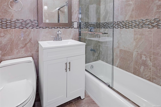 full bathroom with tile patterned floors, toilet, shower / bath combination with glass door, and tile walls