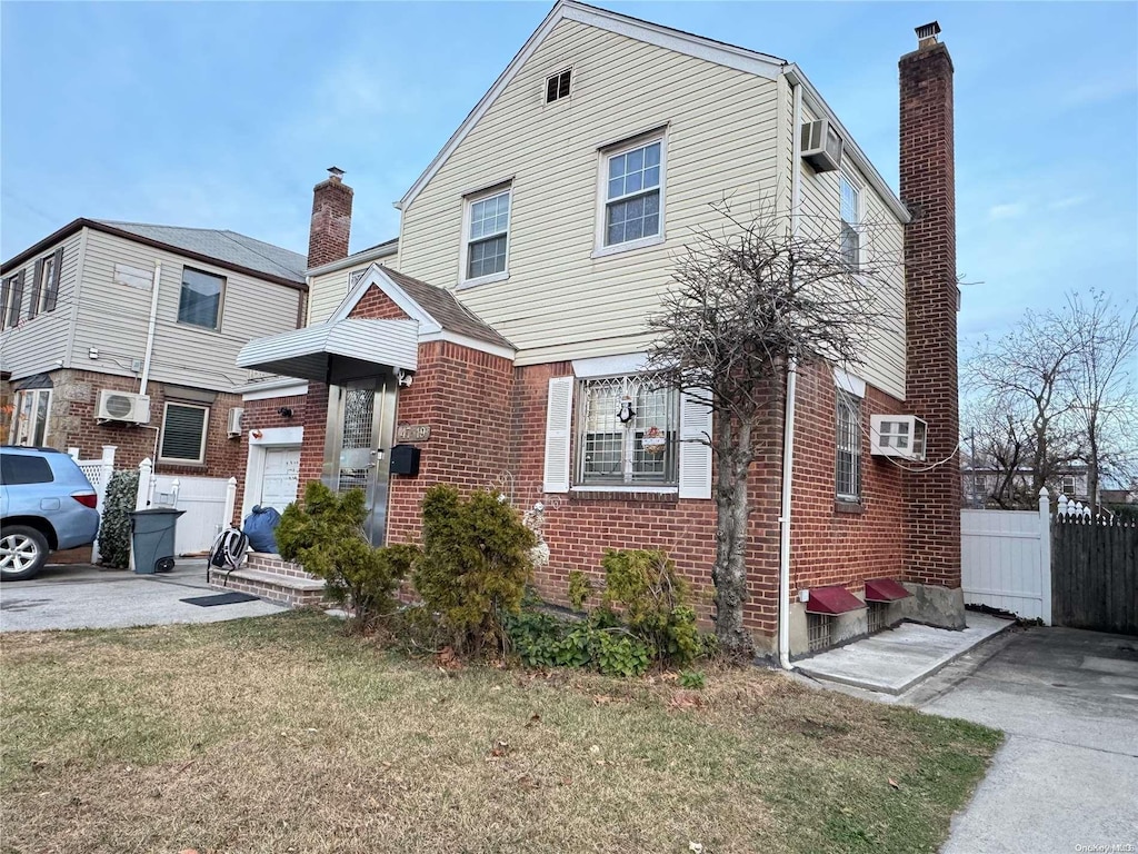 view of front of property featuring a wall mounted air conditioner and a front lawn