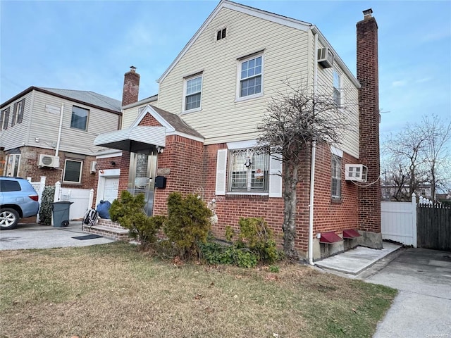 view of front of property featuring a wall mounted air conditioner and a front lawn