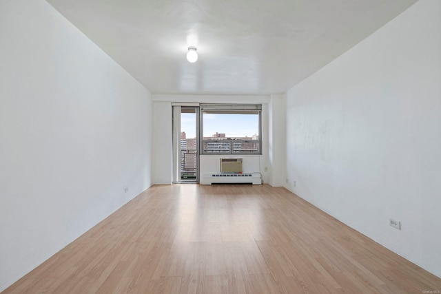 unfurnished living room with a baseboard radiator and light hardwood / wood-style flooring