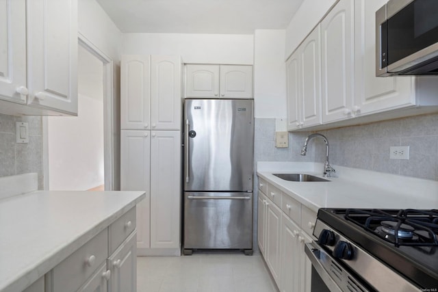 kitchen featuring white cabinetry, sink, light tile patterned floors, and stainless steel appliances