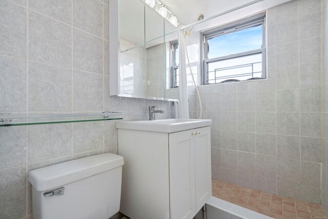 bathroom with toilet, a shower, tile walls, and vanity