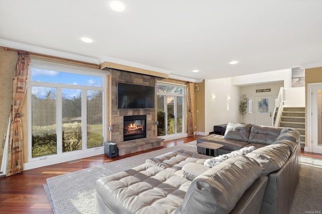 living room with a healthy amount of sunlight, dark hardwood / wood-style flooring, ornamental molding, and a tiled fireplace