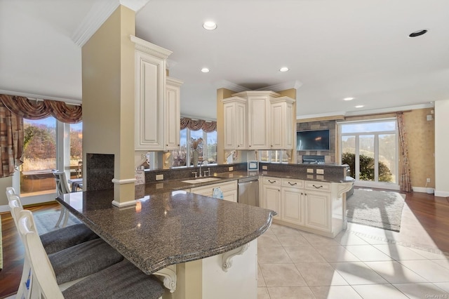 kitchen with sink, kitchen peninsula, crown molding, and a kitchen bar