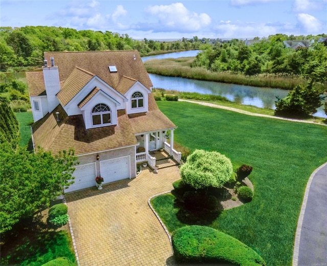 view of front of property with a front lawn, a garage, and a water view