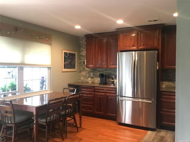 kitchen featuring backsplash, stainless steel refrigerator, and light hardwood / wood-style floors